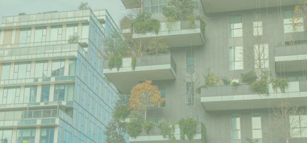 Contemporary glass-front apartment building with balconies filled with greenery and trees nearby
