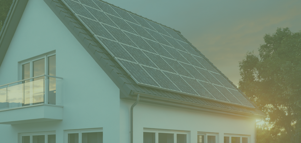 Immagine evocativa per il nuovo Decreto n. 5 del 9 gennaio 2026 (recepimento Direttiva Europea RED III) sulle nuove quote di copertura da fonte rinnovabile in materia di calcolo energetico. Vista su un'abitazione residenziale con pannelli fotovoltaici sul tetto a falde e sole sullo sfondo.